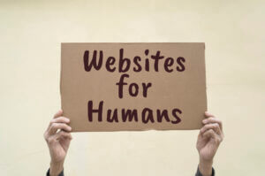 Two hands hold up a cardboard placard that reads 'Websites for Humans'